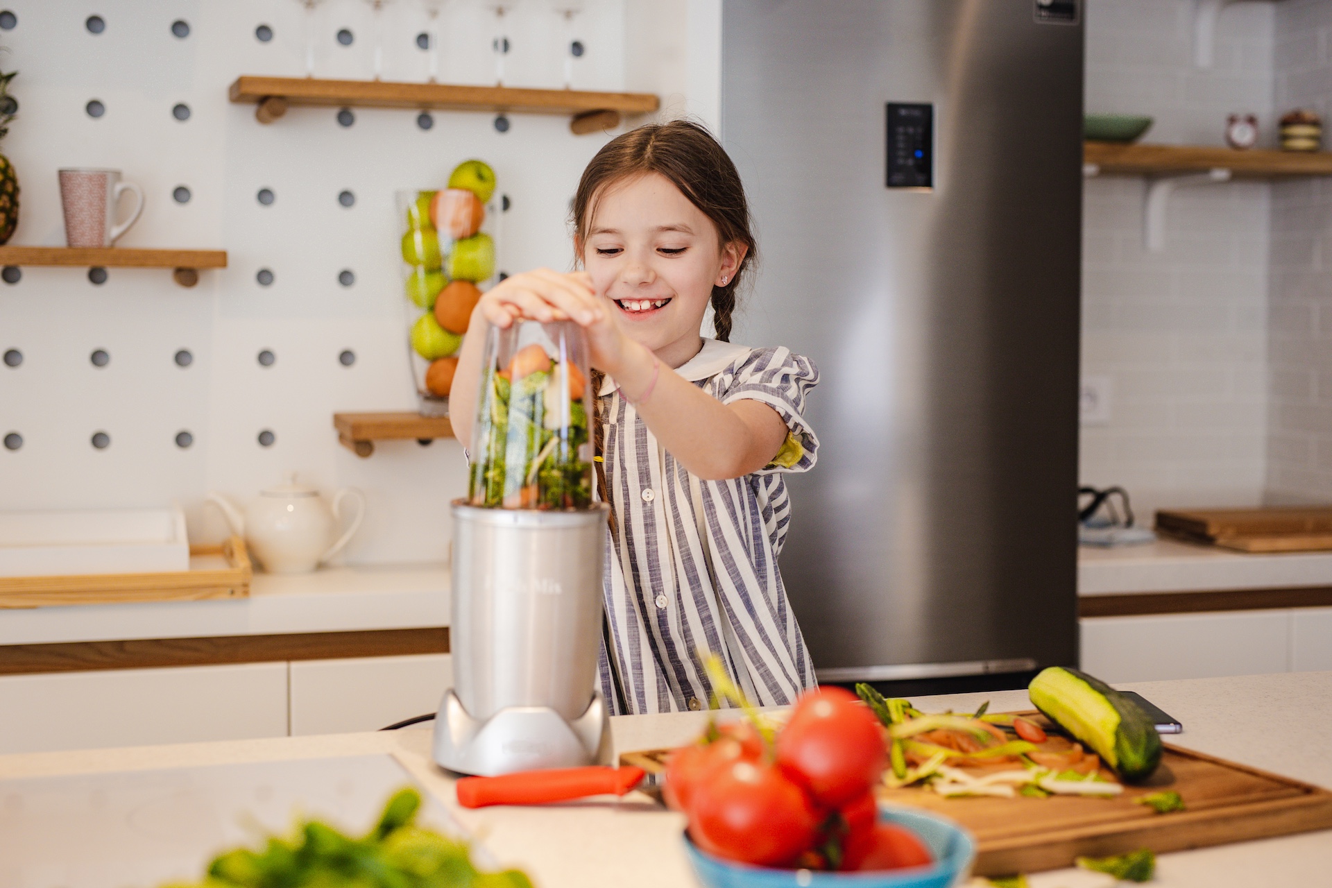 Little girl is making smoothie in the kitchen